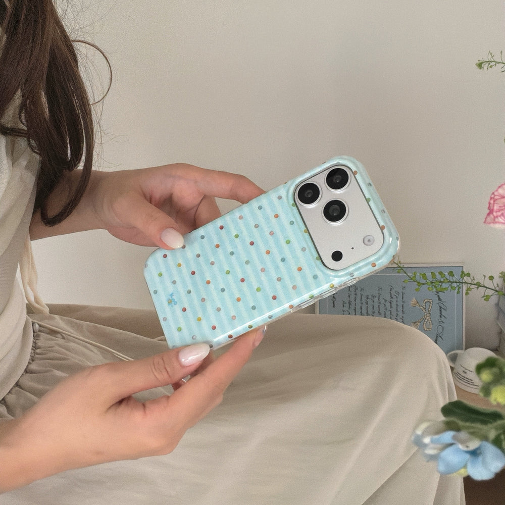 A woman holding an aesthetic blue striped iPhone case horizontally in her hands showing the silver camera plate.