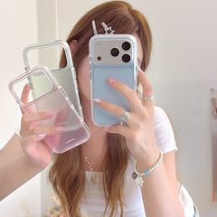 A young woman holding three aesthetic pastel phone cases in blue, pink, and green during a mirror selfie.
