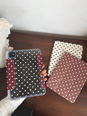 A flat lay showcasing an aesthetic polka dot iPad case collection in burgundy, white, and black-clear variations on a dark wood desk.