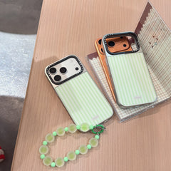 Two aesthetic striped phone cases in silver and orange camera variants placed on a wooden table.