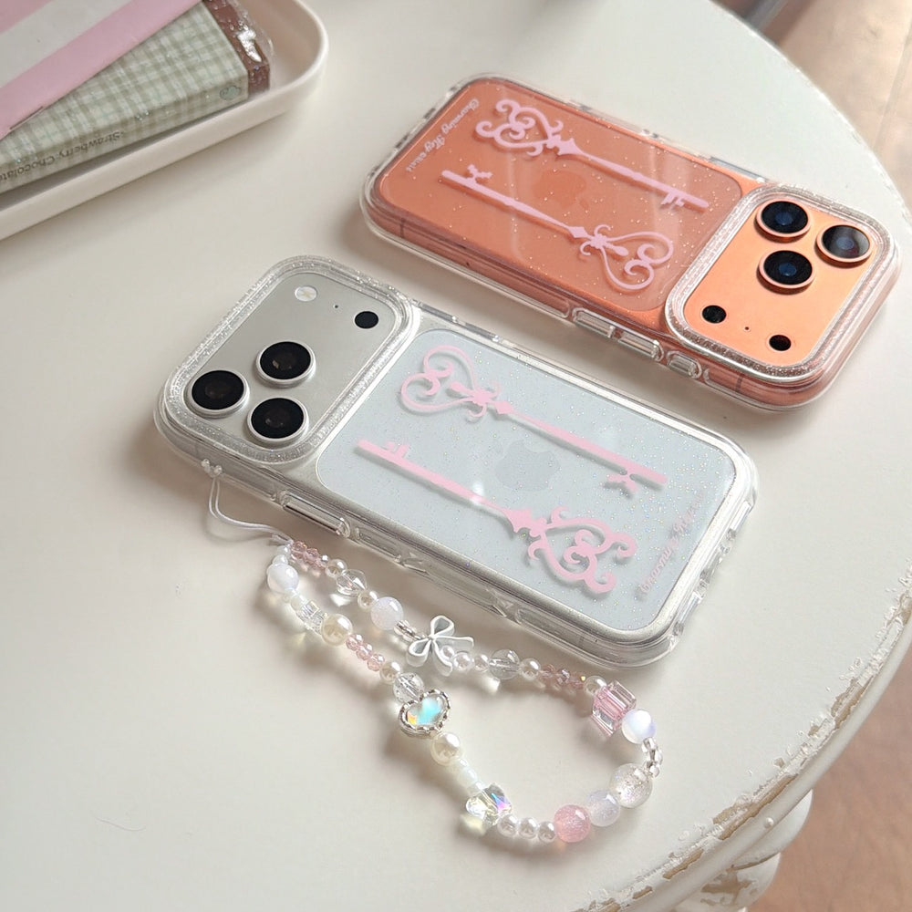 Two balletcore aesthetic charming key phone cases in silver and orange glitter lying flat on a white table.