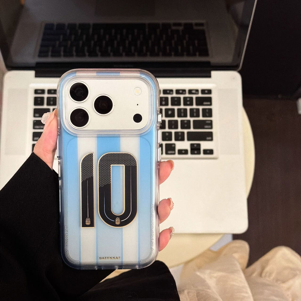 Hand holding a blue soccer jersey iPhone case with No.10 graphic near a laptop