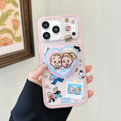 Pink clear cartoon couple iPhone case with round grip stand visible.