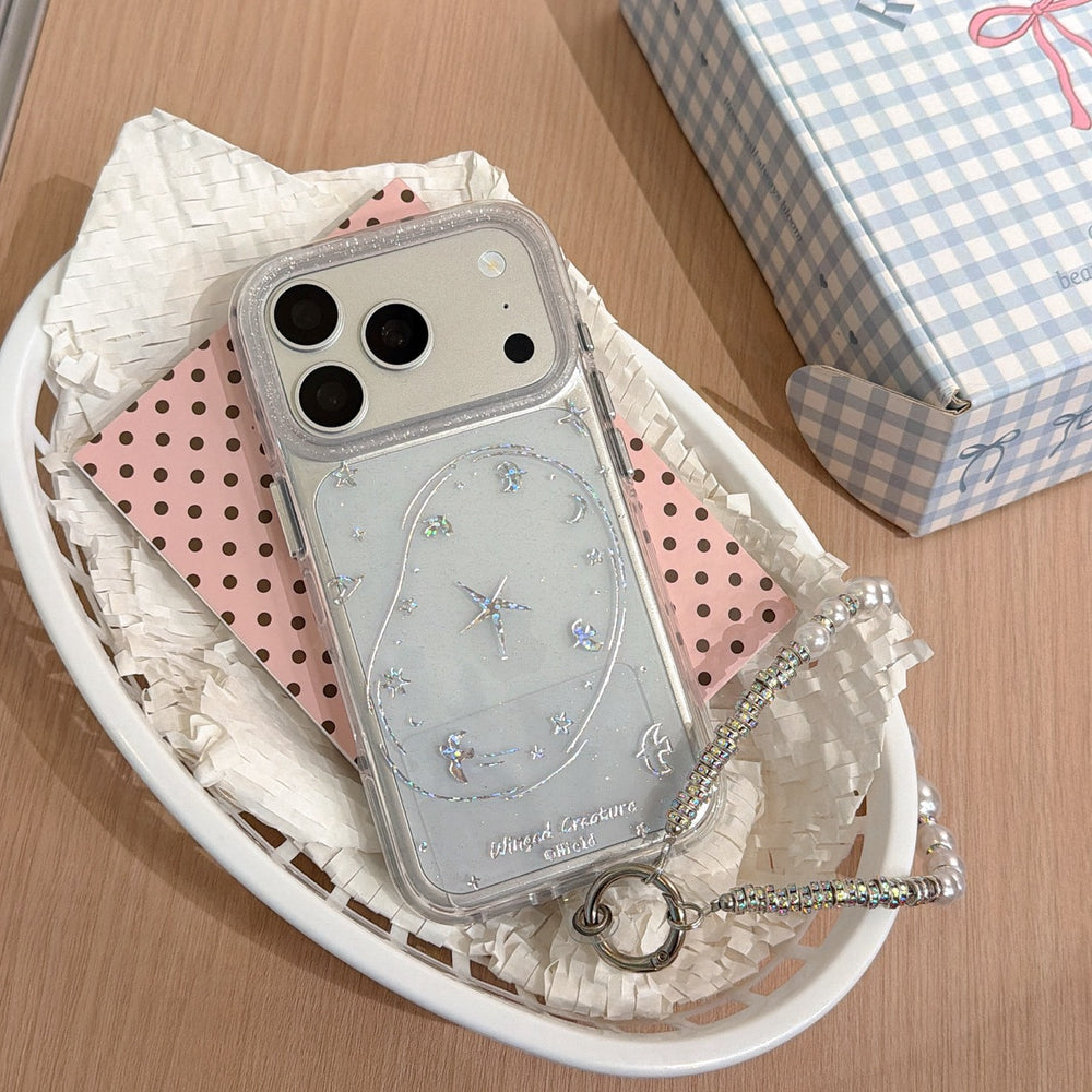 A clear silver glitter iPhone case with romantic star and moon line doodles resting inside a white basket with pink polka dot paper.
