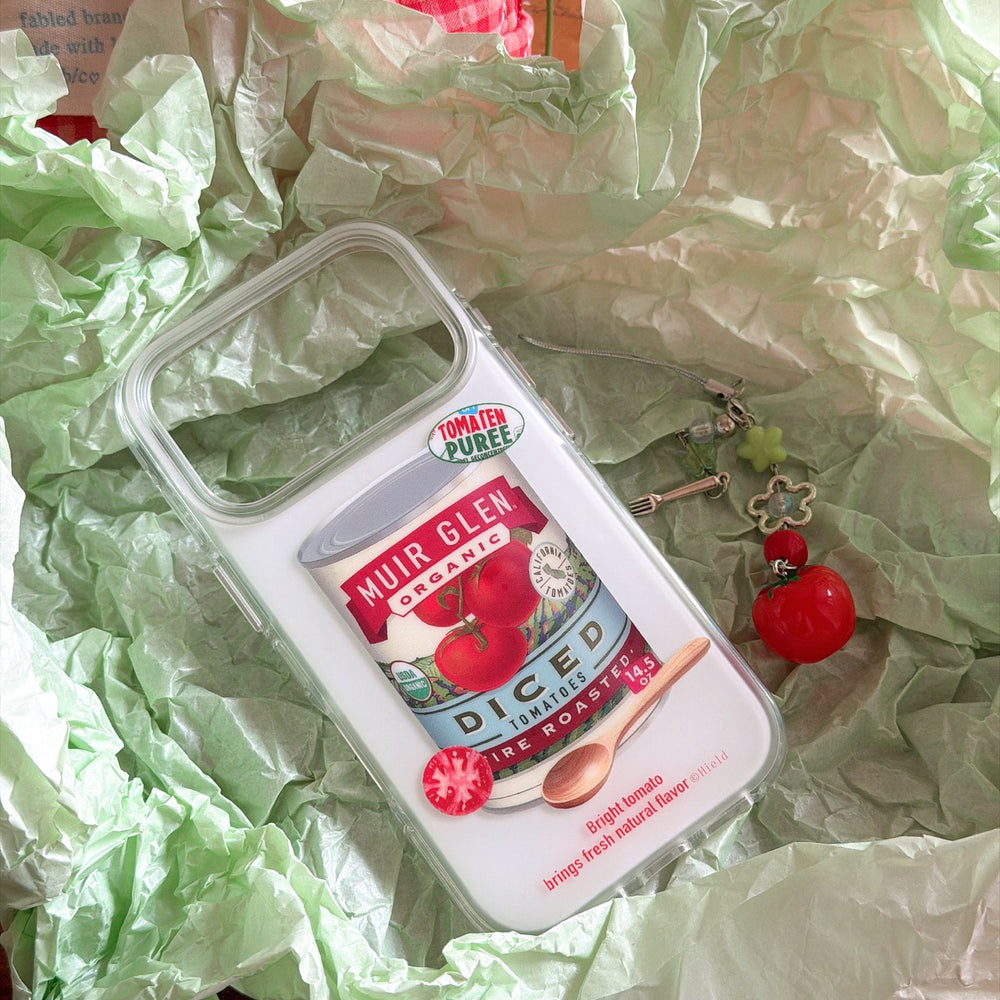 A clear shockproof tomato design iPhone case packaged in green crinkled wrapping paper with its charm lanyard.