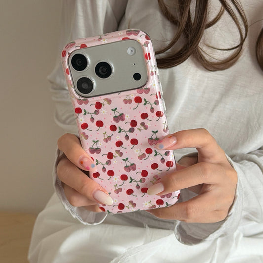 A close-up of a girl holding a coquette aesthetic pink cherry phone case with both hands.