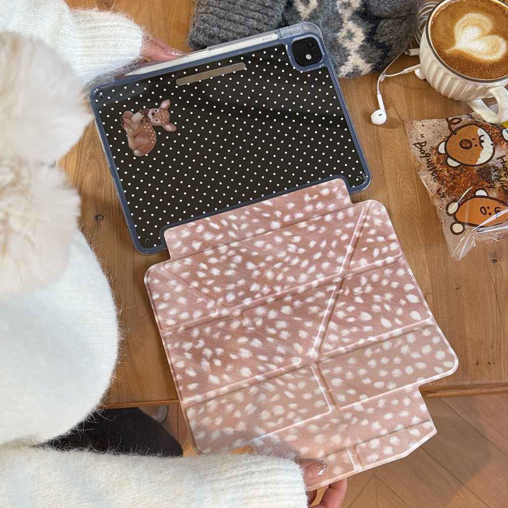 An overhead shot of a cute aesthetic origami folding iPad stand cover laid flat on a wooden surface next to a cup of coffee and a grey winter hat.