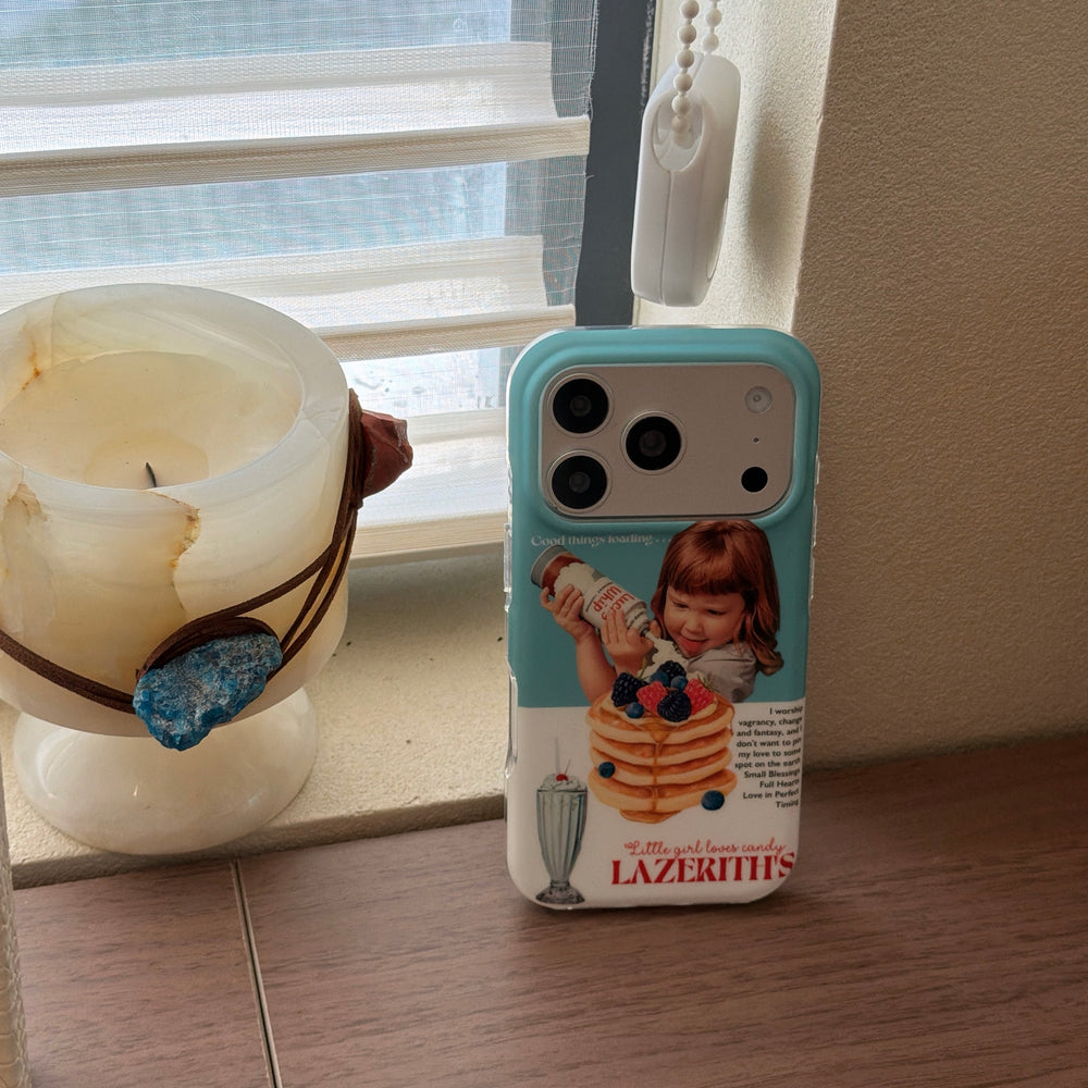 A cute blue bumper pancake graphic iPhone case standing upright on a windowsill next to a candle.