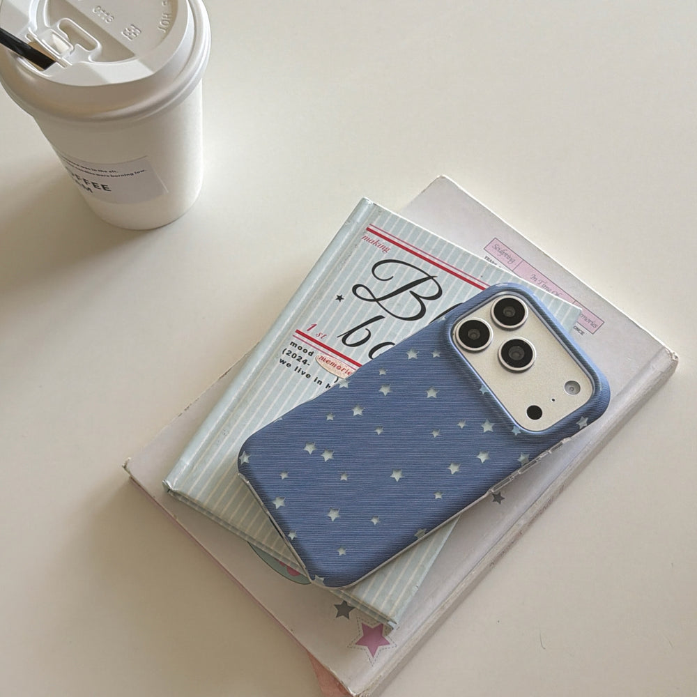 A cute blue star iPhone case resting on aesthetic books next to a takeaway coffee cup.