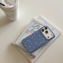 A cute blue star iPhone case resting on aesthetic books next to a takeaway coffee cup.