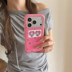 A close-up view of a woman holding a cute pink heart iPhone case against a grey shirt.