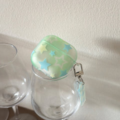 A translucent starry mint green AirPods case balanced on top of an empty clear wine glass.