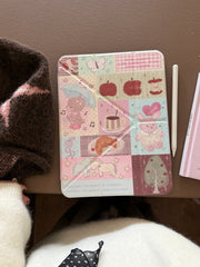 Top-down flat lay view of a closed cute teddy bear patchwork iPad case on a brown table next to a white stylus pencil.