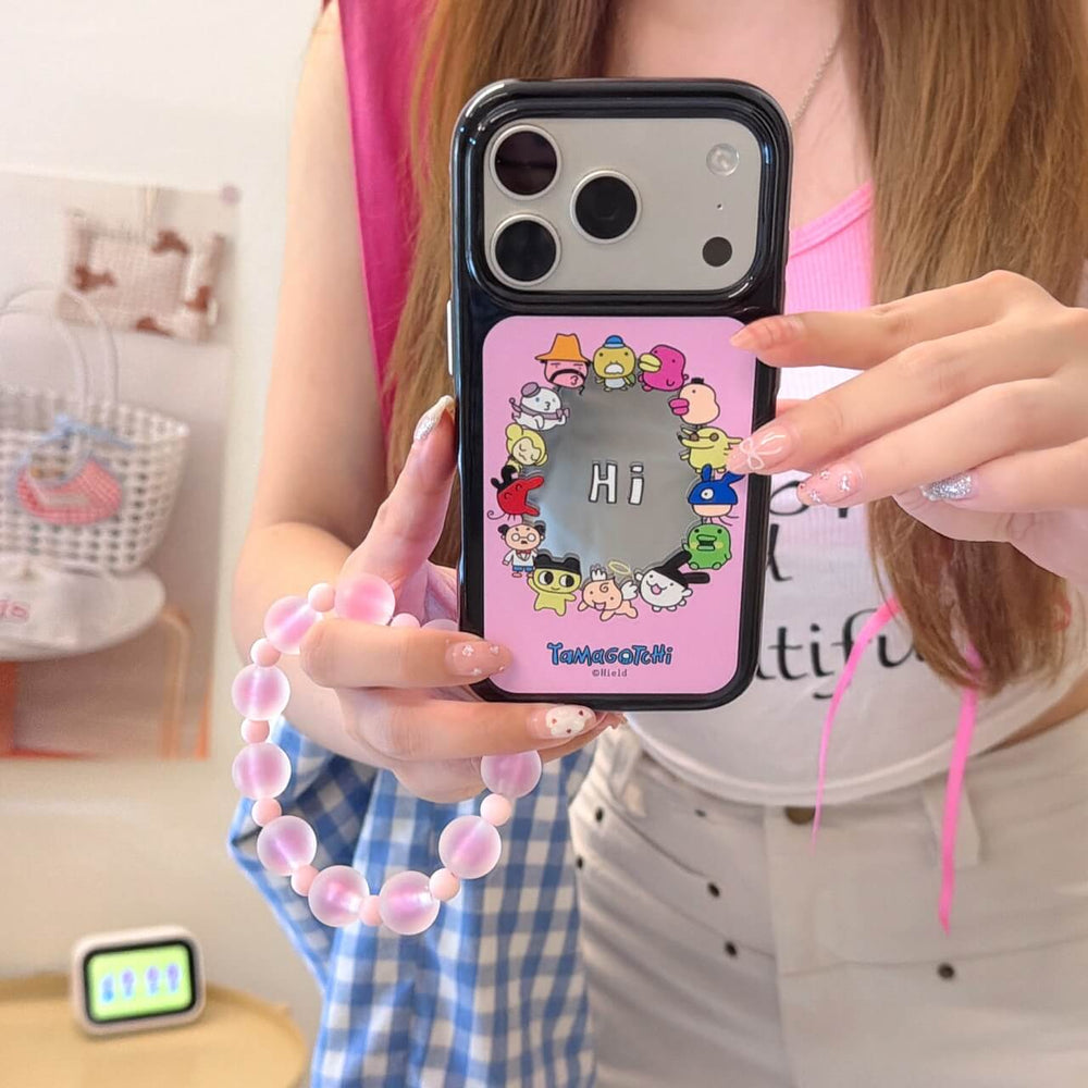 A girl holding the pink Tamagotchi cartoon mirror phone case showing the silver top plate.