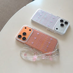 Two clear glitter phone cases with pink rose fence designs on a white table.