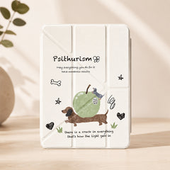 A professional product studio shot of a funny sausage dog ipad cover standing vertically on a light wooden tabletop, with soft warm lighting and a blurred green plant in the background.