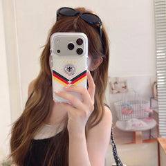 Lifestyle mirror selfie showing a clear iPhone case with German flag colors and a silver camera frame.