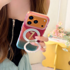 Close-up of a gold iPhone in a clear protective case with a red to teal gradient pattern, highlighting the unfolded circular metal stand and number 7 design.