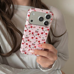 A close-up view of a person holding a kawaii pink cherry iPhone cover showing an aesthetic pattern.