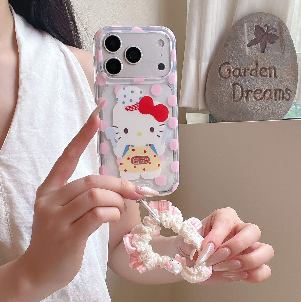 A person holding a pink polka dot kitty phone case by its matching pink lace ruffled scrunchie wrist strap.