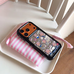 The orange-framed Hello Kitty mirror phone case resting on a pink striped lifestyle pouch with a braided strap.
