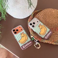 Two clear vertical-striped banana phone cases placed next to a woven straw hat and a white planter.