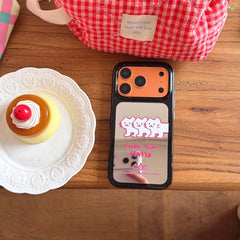 An orange kawaii cat mirror phone case placed flat on a wooden desk next to a sweet pudding dessert.