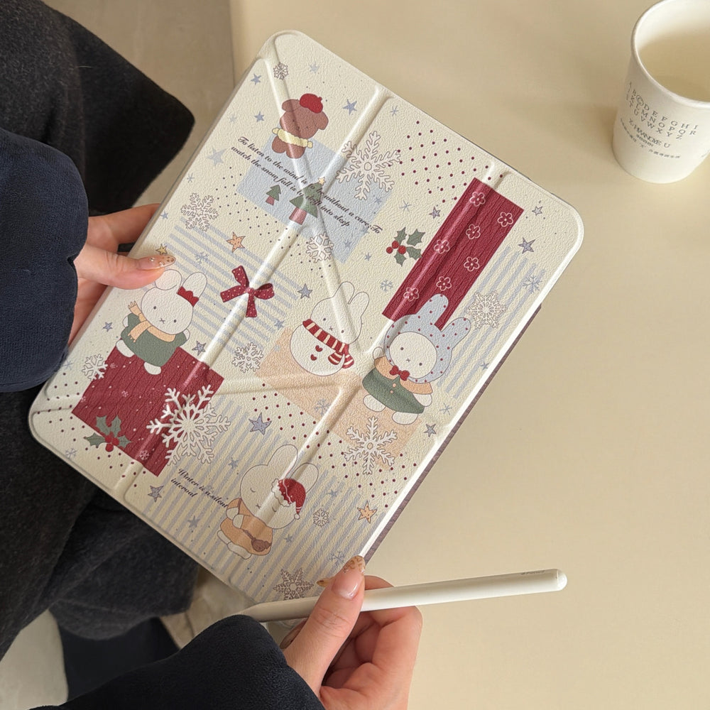 A user holding a closed kawaii Miffy iPad case alongside a white stylus pencil, creating a cozy aesthetic workspace setup next to a coffee cup.