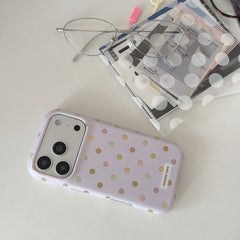 A kawaii purple polka dot iPhone case on a desk next to silver glasses and stationery.