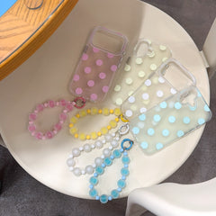 Four Korean style pastel polka dot phone cases arranged on a chair with colorful frosted bead wristlets.