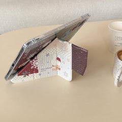 Side view of a kawaii Miffy iPad case folded into a stable origami stand on a beige desk, showcasing the cute winter bunny illustration on the smart cover.