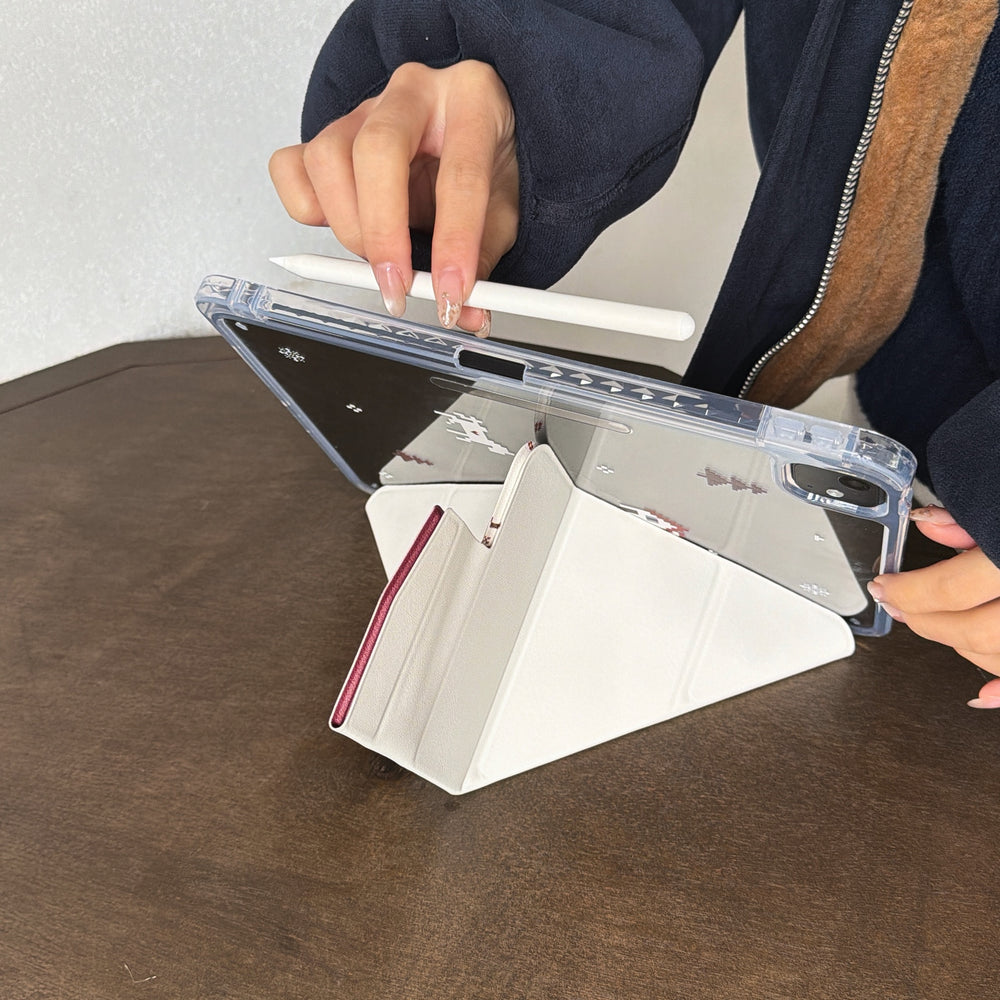 A close-up of hands adjusting a multi-angle magnetic iPad stand while attaching a white stylus pencil to the magnetic side of the clear acrylic shell.
