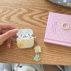 An open yellow plaid AirPods case with white earbuds inside lying on a wooden desk next to a pink notebook.