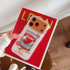 A hand holding the orange metallic camera frame tomato case over a bright red vintage book.