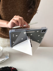 The vintage patchwork iPad case set up on a white desk in landscape mode using its white origami folding stand, paired with a hand holding a stylus pencil.