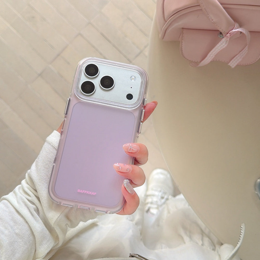 Top-down view of a hand holding a purple-pink aesthetic iPhone case over a white outfit lifestyle background.