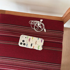 A retro mustache pattern iPhone case lying flat on a red and brown striped chair seat.