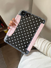 A close-up handheld shot showing the transparent back panel of a retro polka dot ipad case with light pink magnetic edges on a black iPad.