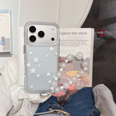 A person holding a clear silver star iPhone case with a frosted beaded wristlet over an open book.