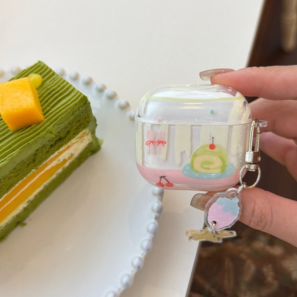 A hand holding a sweet dessert AirPods case next to a green matcha layered pastry on a table.