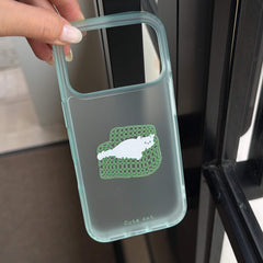 A hand holding a transparent mint green iPhone case showing the couch cat graphic insert.