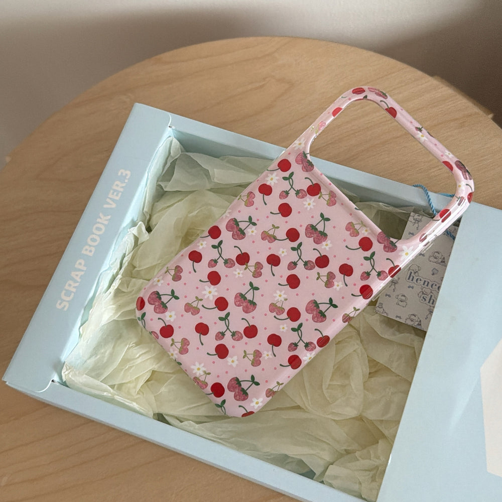 A vintage cherry iPhone case inside a light blue product gift box with white tissue paper.