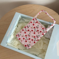 A vintage cherry iPhone case inside a light blue product gift box with white tissue paper.