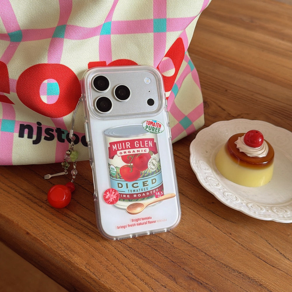 A vintage tomato soup phone case resting next to a colorful checkered tote bag and a pudding plate.