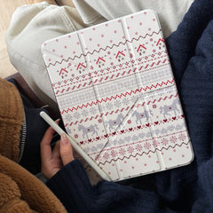 A close-up view of a person wearing a cozy winter sweater holding a Nordic-patterned winter aesthetic iPad cover while holding a white stylus pencil in their hand.
