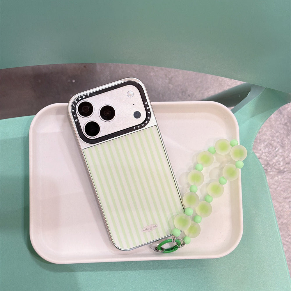 Y2K style green stripe phone case with a beaded strap sitting on a white minimalist tray.