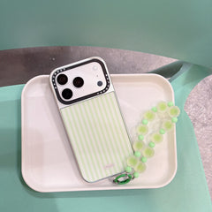 Y2K style green stripe phone case with a beaded strap sitting on a white minimalist tray.