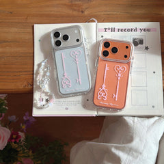 Silver and orange Y2K magic key phone cases placed flat on an open aesthetic notebook.