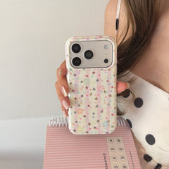A close-up of a y2k pink striped star iPhone case held in front of a pink spiral notebook.