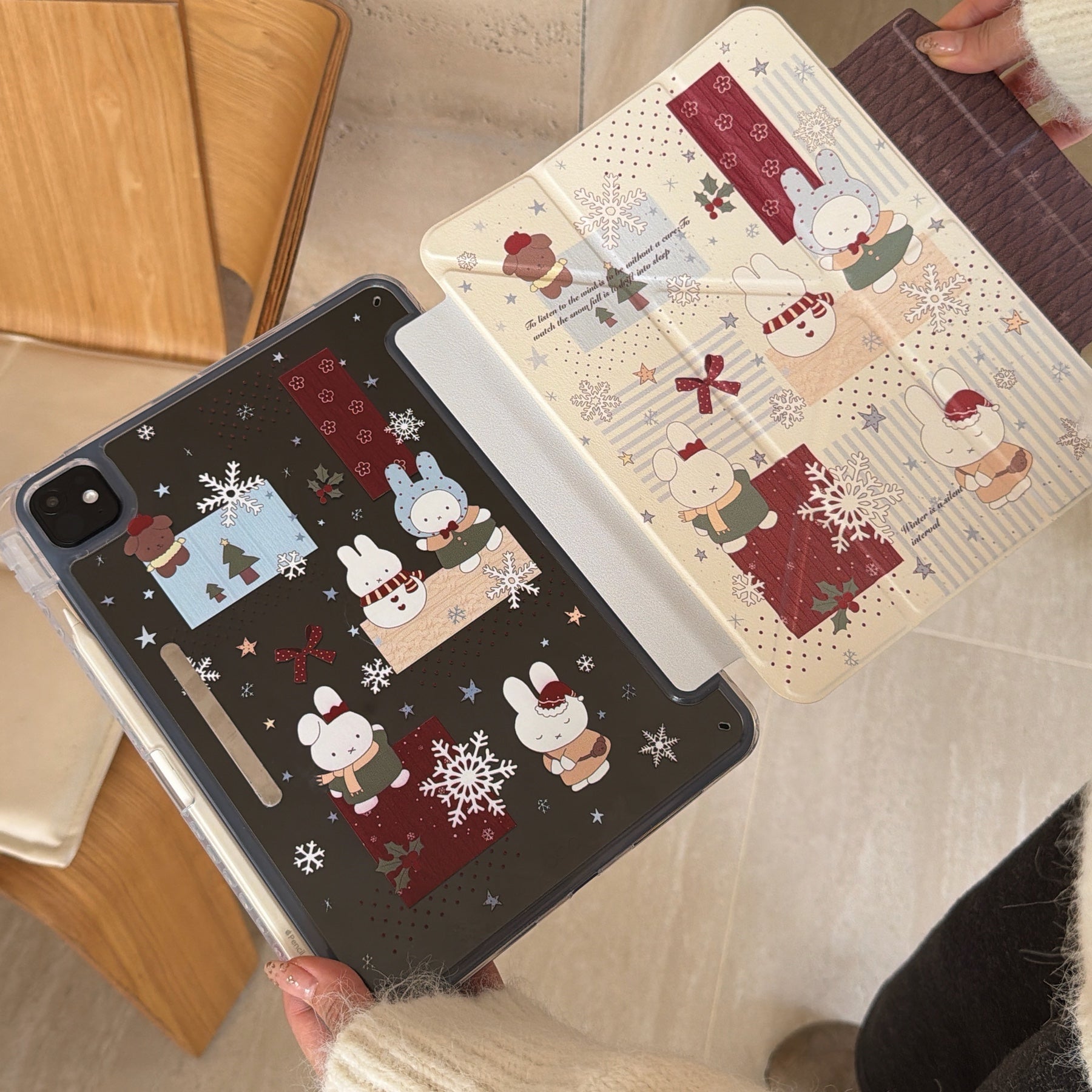 Hands separating the magnetic detachable smart cover from the clear back panel of a cute Miffy iPad case, showcasing the matching winter story patterns on both sides.
